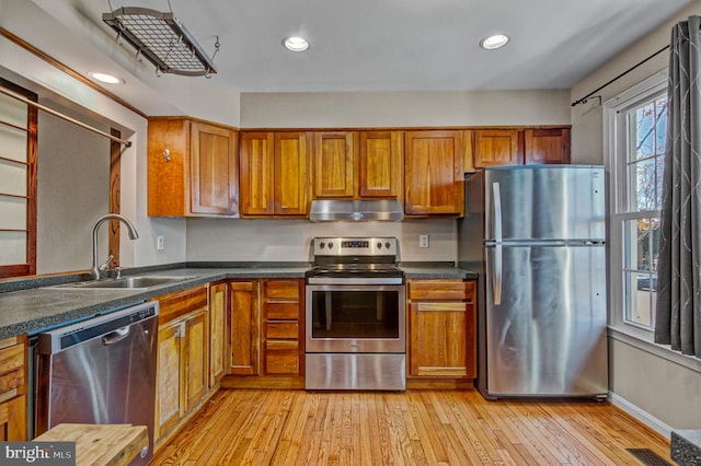 kitchen with brown cabinets, extractor fan, stainless steel appliances, and a sink