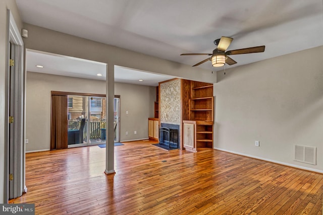 unfurnished living room featuring a large fireplace, light wood-style flooring, visible vents, and baseboards