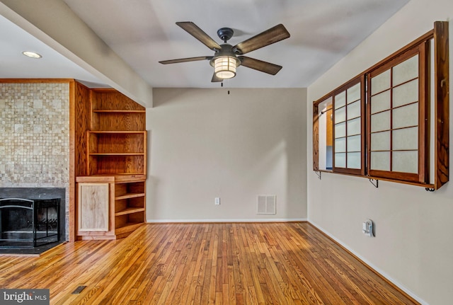 unfurnished living room with baseboards, hardwood / wood-style flooring, visible vents, and built in features