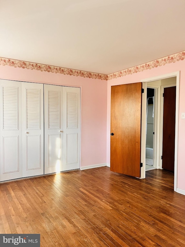 unfurnished bedroom with a closet, baseboards, and hardwood / wood-style flooring