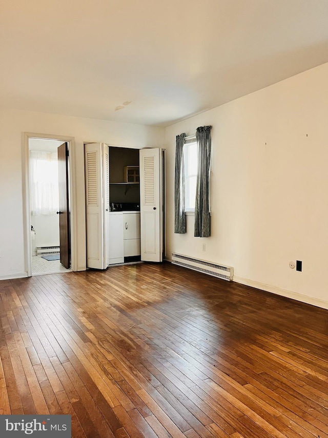 spare room featuring baseboard heating, hardwood / wood-style floors, and washing machine and clothes dryer