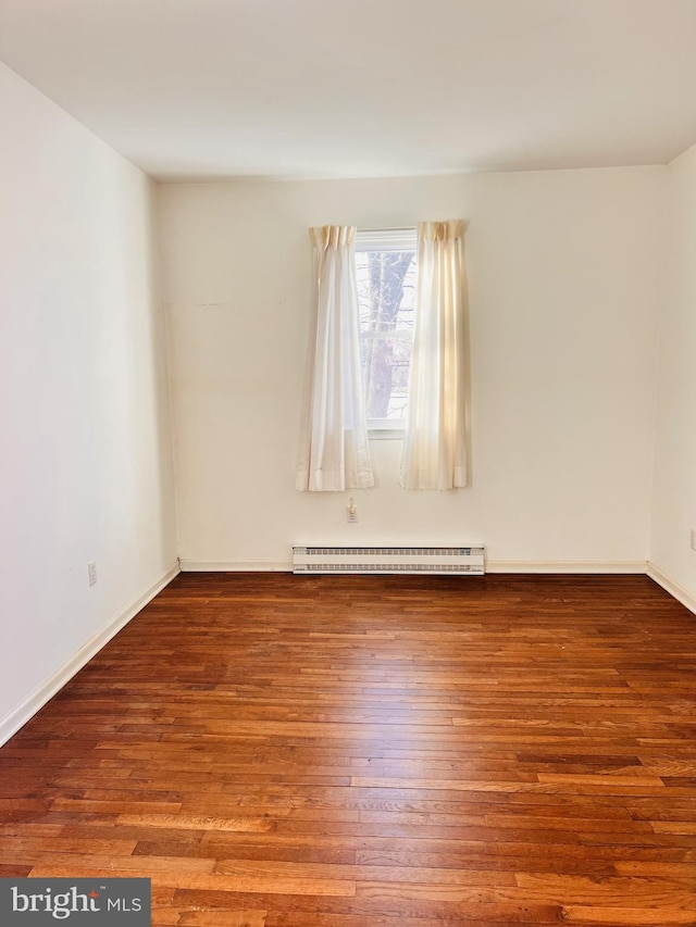 unfurnished room with baseboards, baseboard heating, and wood finished floors