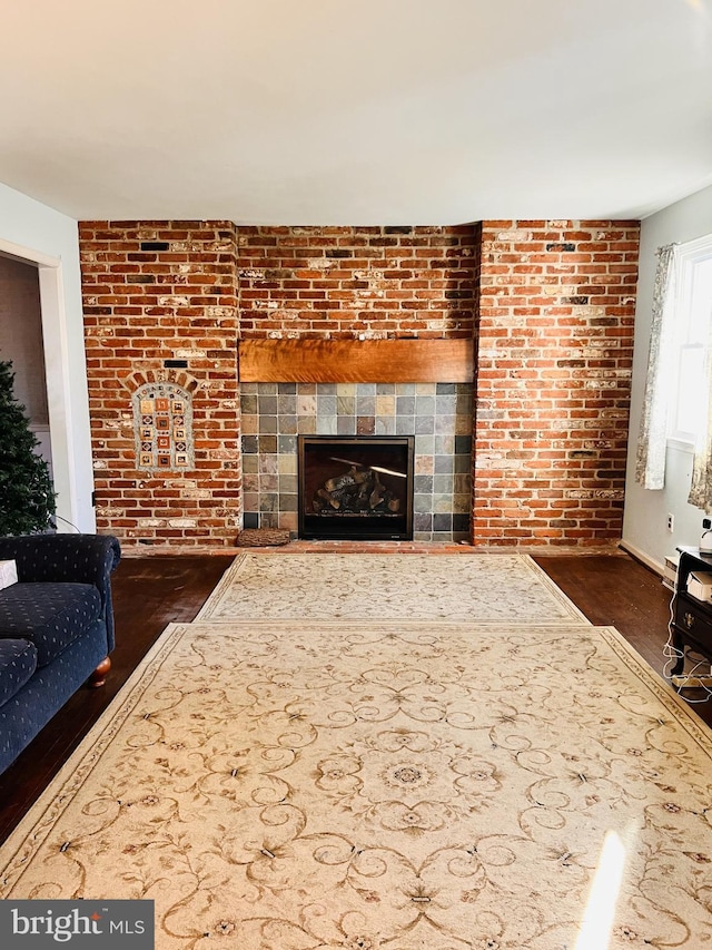 living room with brick wall, wood finished floors, and a fireplace