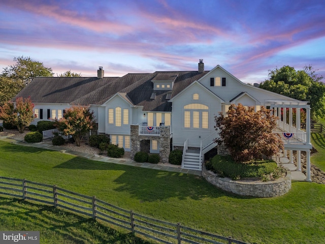 view of front of home with stairs, a front lawn, a chimney, and fence