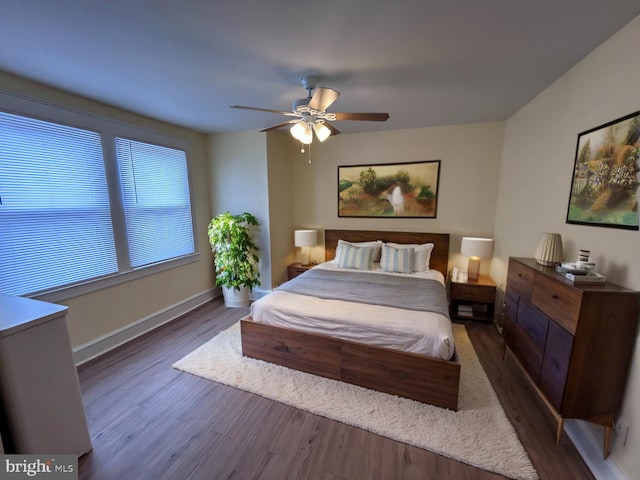 bedroom with dark wood-style floors, ceiling fan, and baseboards