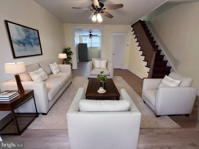 living area featuring light wood-style floors, stairs, and a ceiling fan