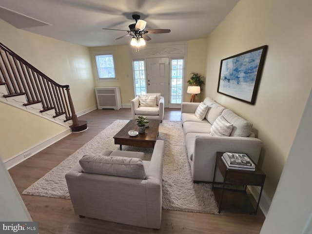 living area featuring stairs, plenty of natural light, wood finished floors, and baseboards