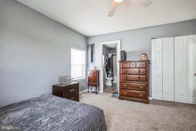 carpeted bedroom with a closet, ensuite bath, a ceiling fan, and baseboards