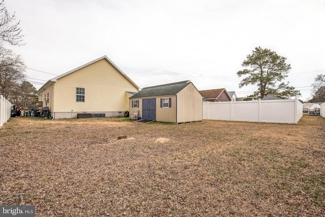 back of property featuring a yard, a fenced backyard, a storage unit, and an outdoor structure