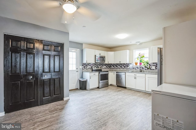 kitchen with light wood finished floors, tasteful backsplash, stainless steel appliances, and a wealth of natural light