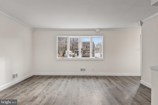 spare room featuring baseboards, ornamental molding, visible vents, and light wood-style floors