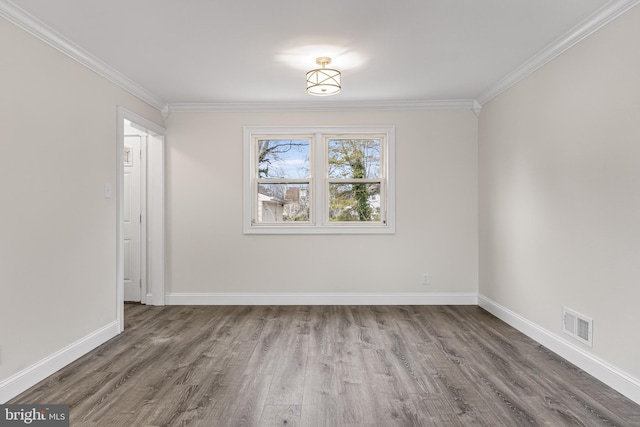 spare room featuring ornamental molding, wood finished floors, visible vents, and baseboards