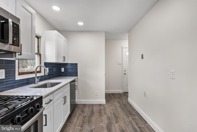 kitchen featuring a sink, white cabinetry, light countertops, appliances with stainless steel finishes, and decorative backsplash