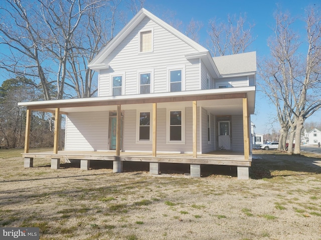 view of front of house with a front lawn, a porch, an attached carport, and roof with shingles