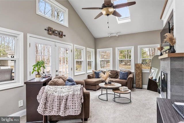 sunroom / solarium with vaulted ceiling with skylight, plenty of natural light, a glass covered fireplace, and french doors