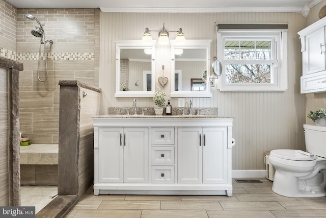 full bath featuring toilet, a tile shower, and a sink