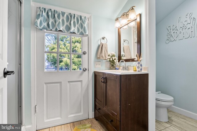 bathroom with baseboards, vanity, toilet, and wood finished floors