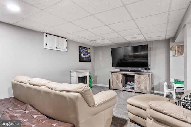 living room with carpet, a fireplace, baseboards, and a drop ceiling