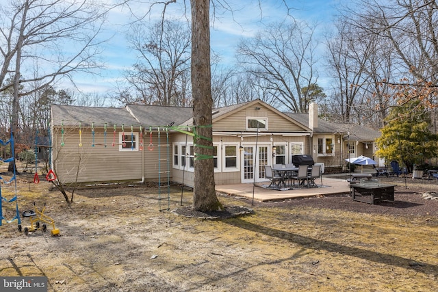 rear view of property featuring french doors, a playground, a patio, and a chimney