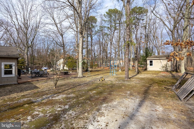 view of yard featuring an outdoor structure, a wooden deck, and a storage shed