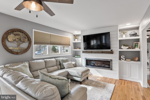 living area with light wood-style floors, recessed lighting, a fireplace, and a ceiling fan