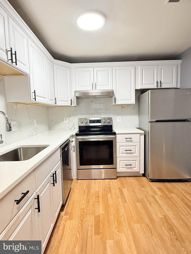 kitchen featuring light wood-type flooring, white cabinetry, stainless steel appliances, and a sink