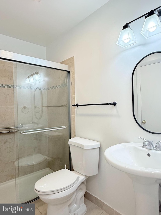 full bathroom featuring a stall shower, baseboards, toilet, tile patterned floors, and a sink