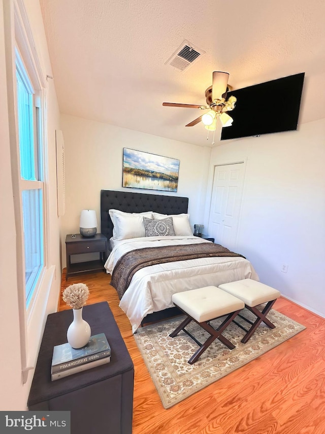 bedroom with a closet, visible vents, ceiling fan, a textured ceiling, and wood finished floors