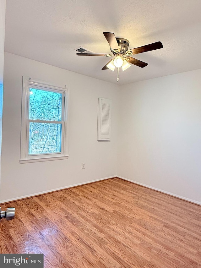 spare room featuring a textured ceiling, wood finished floors, a ceiling fan, and baseboards