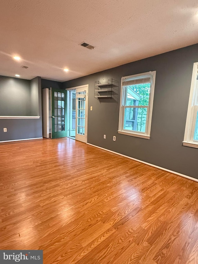 unfurnished room featuring visible vents, a textured ceiling, and wood finished floors