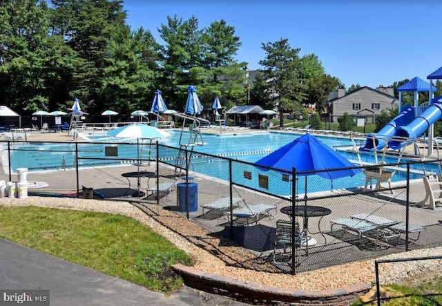 community pool featuring central AC unit, a patio area, fence, and a water slide