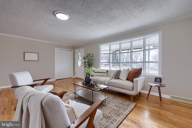 living area featuring visible vents, light wood-style flooring, and crown molding