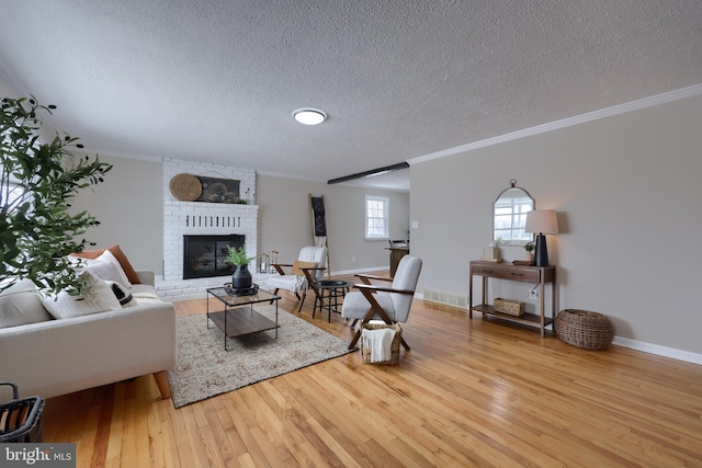 living room featuring visible vents, a brick fireplace, crown molding, baseboards, and wood finished floors