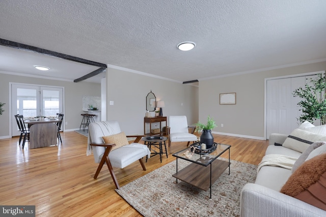 living room featuring crown molding, light wood-style floors, baseboards, and a textured ceiling