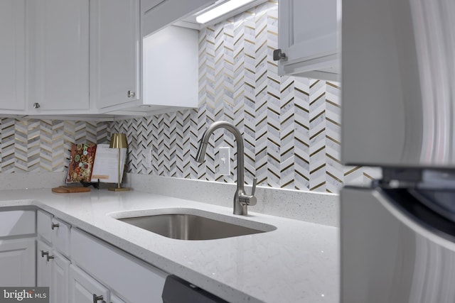 kitchen with white cabinetry, light stone counters, tasteful backsplash, and a sink