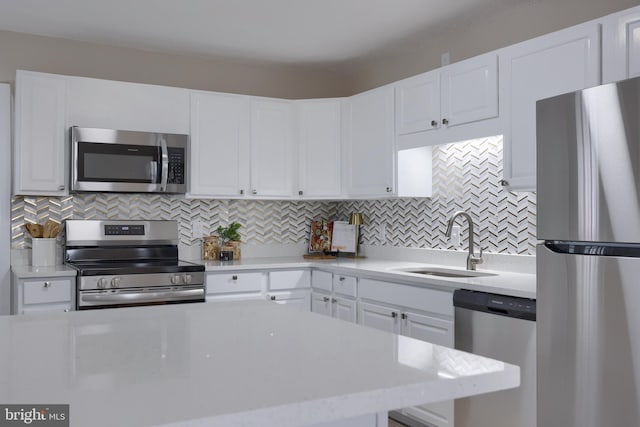 kitchen featuring a sink, tasteful backsplash, appliances with stainless steel finishes, and white cabinets