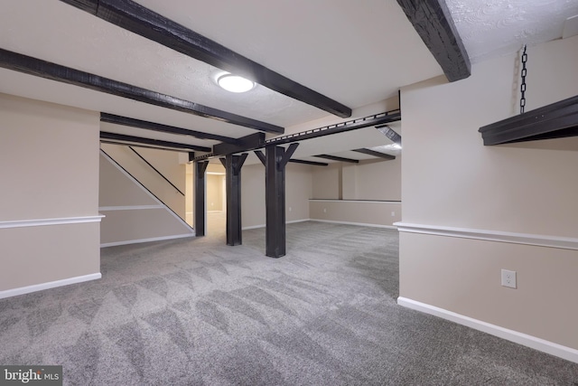 finished below grade area with a textured ceiling, baseboards, and carpet floors