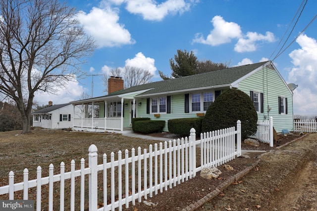 ranch-style house featuring roof with shingles, covered porch, a fenced front yard, and a chimney