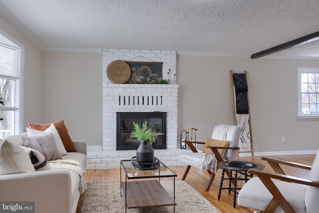 living room featuring crown molding, a brick fireplace, wood finished floors, and a textured ceiling