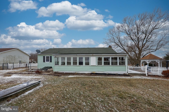 back of property featuring a gazebo, a sunroom, and fence