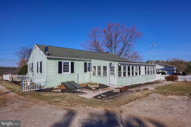 view of front of house with a chimney, fence, roof with shingles, and a sunroom