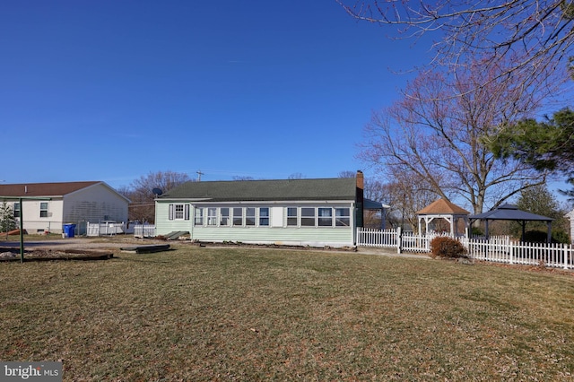 rear view of property featuring a gazebo, a chimney, a yard, and fence