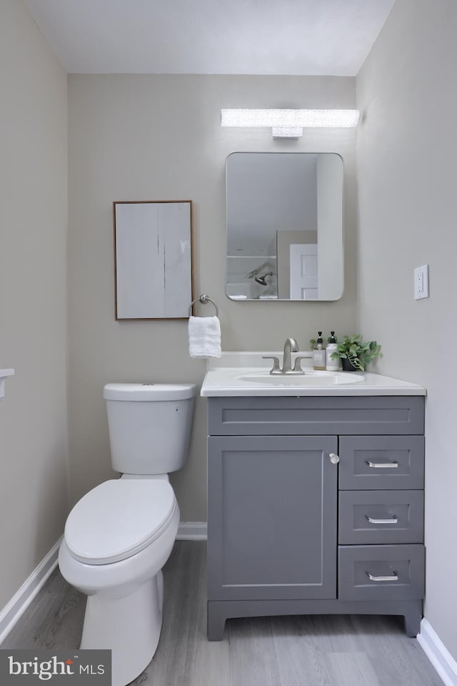 bathroom with toilet, vanity, and baseboards