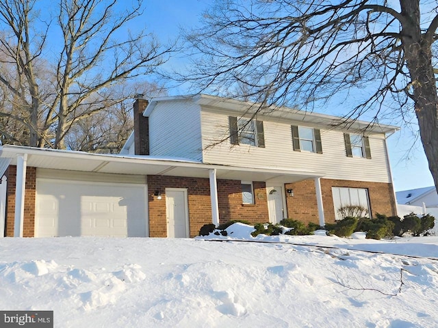 view of front of home with an attached garage, a chimney, and brick siding