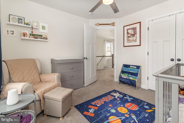 sitting room featuring light colored carpet, ceiling fan, and an upstairs landing