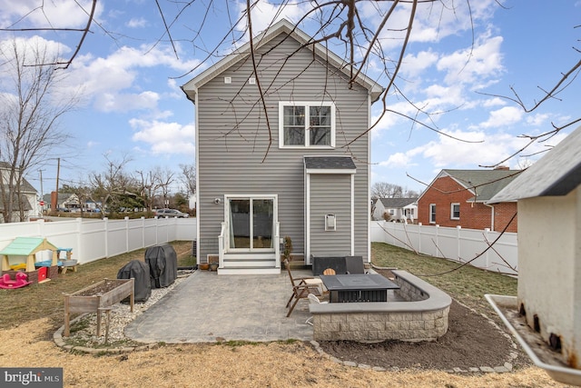 rear view of house featuring entry steps, a fenced backyard, a fire pit, and a patio