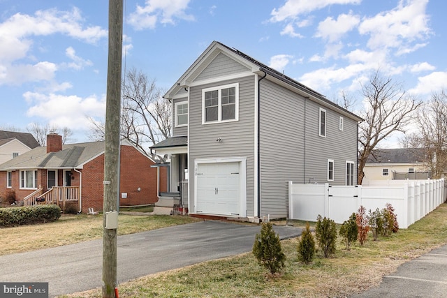 view of front facade featuring a garage, fence, and aphalt driveway