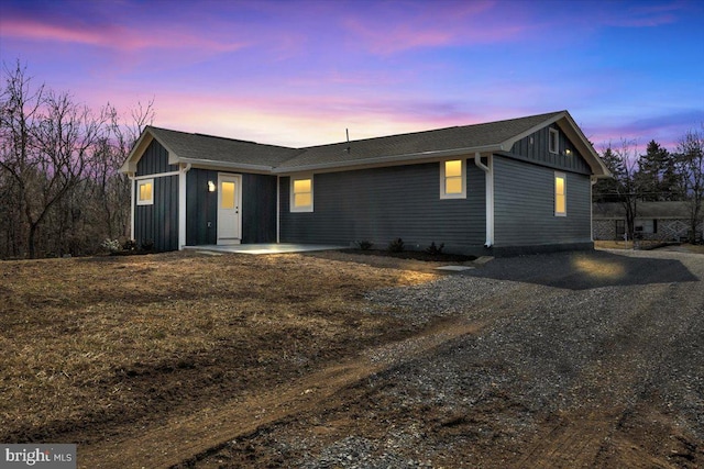 view of front of house featuring driveway, board and batten siding, and a patio area