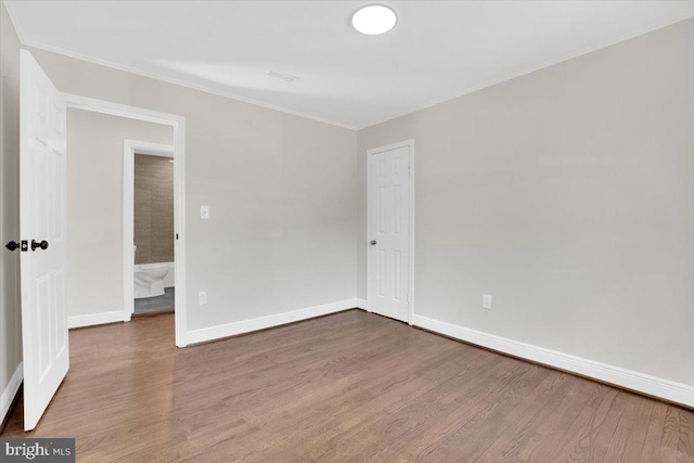 unfurnished bedroom with a closet, baseboards, wood finished floors, and ornamental molding