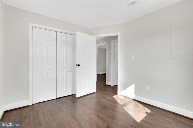 unfurnished bedroom featuring a closet, visible vents, baseboards, and wood finished floors